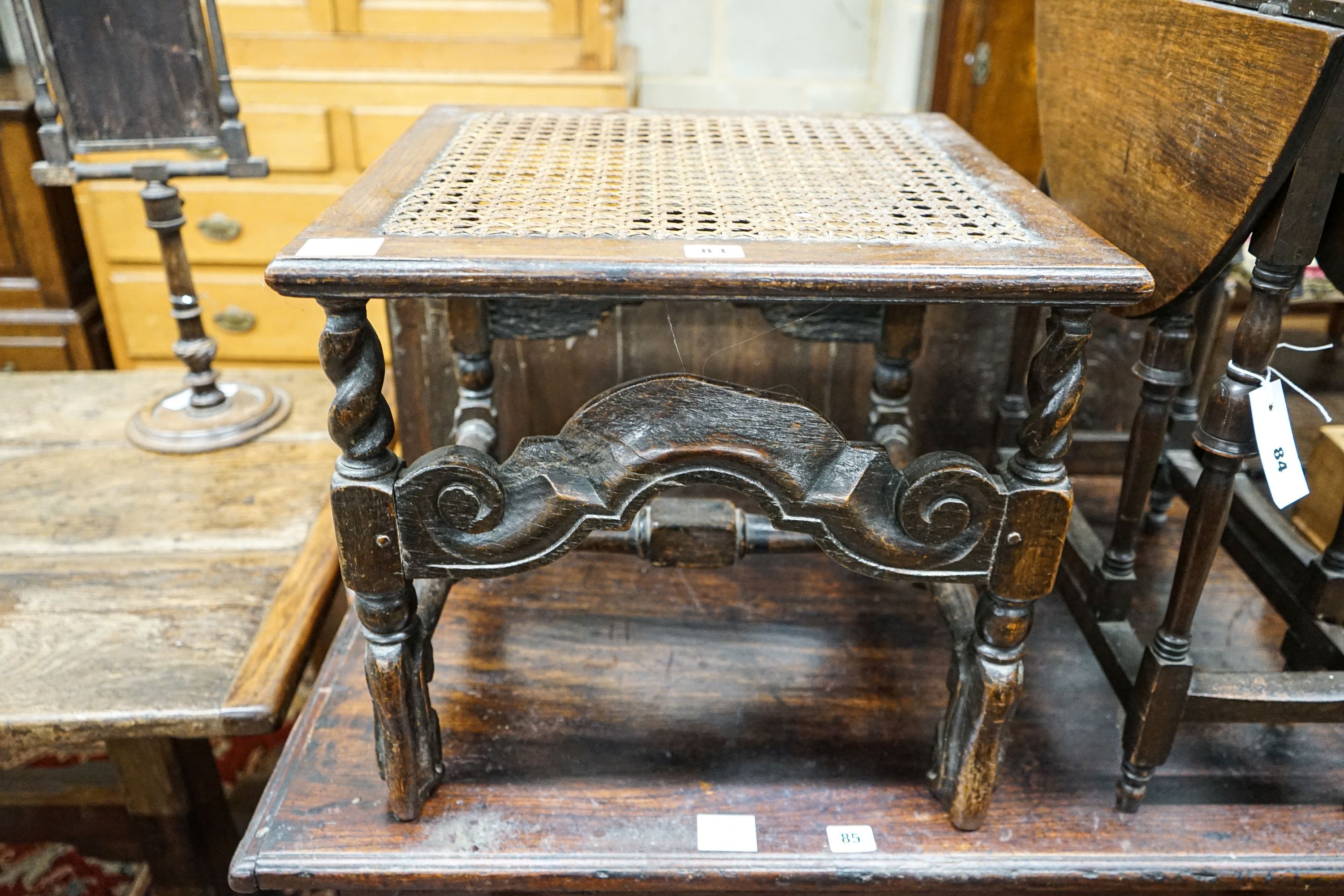 A 17th century style carved oak stool, with caned seat and H stretcher, width 47cm, depth 46cm, height 42cm